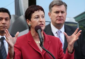 Carol Schatz about to grasp and crush someone or something and making the guy behind her on the right a little queasy.